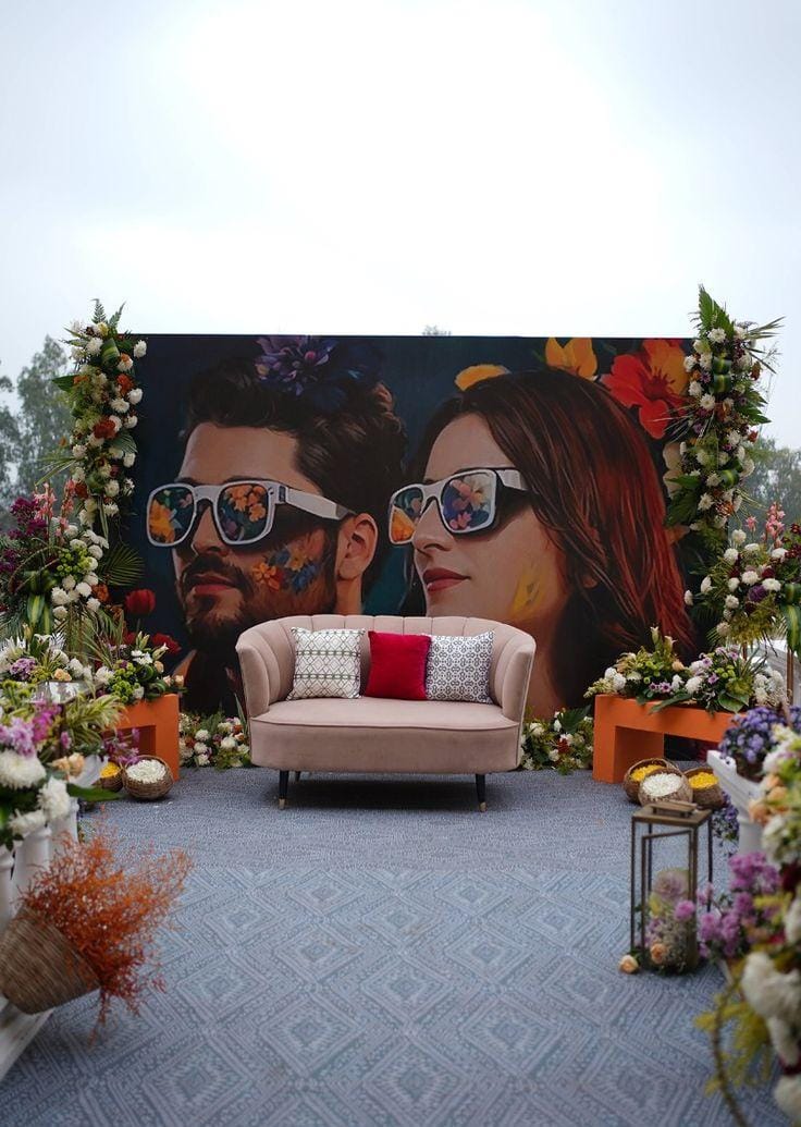 Pop-art wedding backdrop with an illustrated couple, florals and a pink sofa by RAW Group